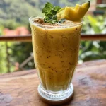 Batido de frutas e espinacas em um copo transparente com gelo.