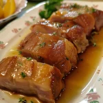 Close-up of a juicy Filé Mignon Suíno Assado na Cerveja, showcasing its golden-brown crust.