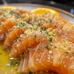 Close-up of cooked salmon fillet with orange sauce, garnished with green onions.