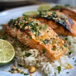 Close-up view of roasted salmon with herbs served over coconut rice.