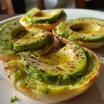 Close-up of a toasted whole grain bread topped with sliced avocado and spices.
