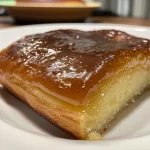 Close-up of a moist slice of Bolo de Fubá Cremoso on a plate.