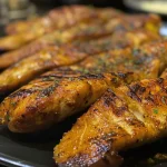 Prato de frango empanado crocante com ingredientes visíveis ao fundo.