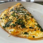 Omelete de espinafre com queijo em primeiro plano, destacando sua textura suculenta.