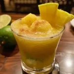 Close-up de um copo de suco de abacaxi com limão siciliano e hortelã.
