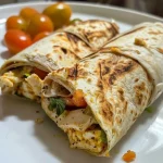Close-up of grilled chicken breast garnished with lemon slices and herbs.