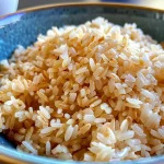 Close-up of a bowl of arroz integral simples with visible grains and herbs.
