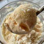 Close-up de pudim de coco gelado com textura cremosa e decorado com coco ralado.