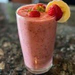 Close-up de um smoothie cremoso de morango e banana em um copo.