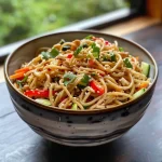 Close-up of cold noodles in peanut sauce, showcasing fresh vegetables and a creamy dressing.