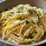 Close-up of a creamy lemon basil pasta dish with fresh basil and Parmesan cheese on top.