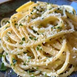 Close-up of a plate of Lemon Pasta with spaghetti, garnished with herbs.