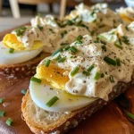 Sanduíche de salada de ovos cremoso com fatias de pão sourdough.