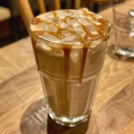Close-up de um Iced Mocha Oat Latte com detalhes de espuma de leite e chocolate.