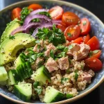 Close-up side view of a colorful Tuna Quinoa Bowl with fresh ingredients.