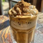 Close-up de um copo de Dalgona Coffee com espuma cremosa e leite.