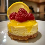 Mini cheesecakes de limão cobertos com creme e framboesas frescas.