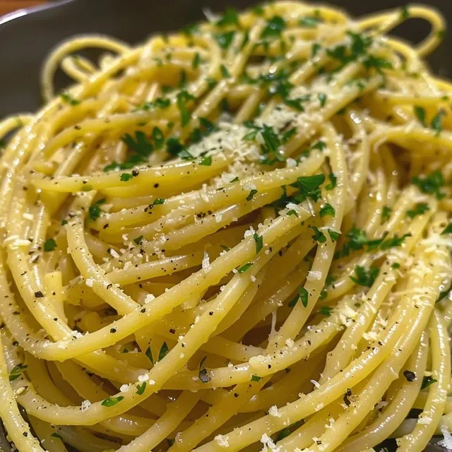 Close de spaghetti com molho à base de limão, decorado com salsinha e pimenta.