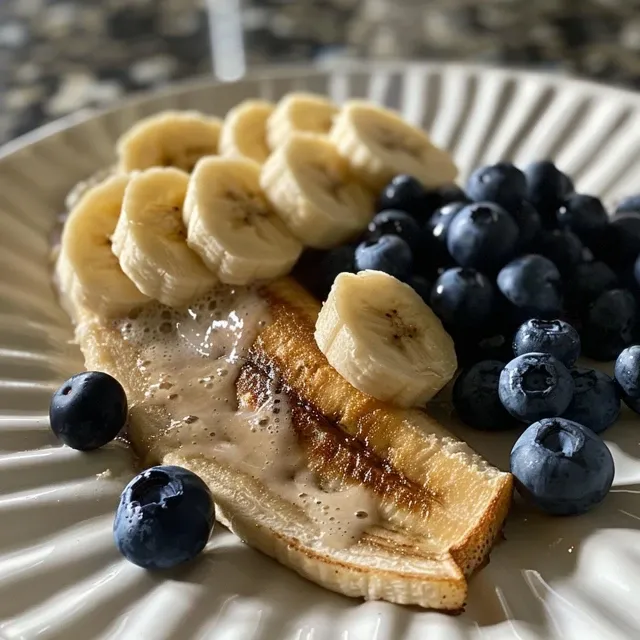 Picolé de banana e mirtilo em um palito, exibindo camadas de frutas e um aspecto congelado.