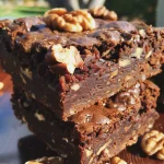 Close-up de brownies de chocolate cru, com textura úmida e ingredientes visíveis ao lado.
