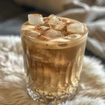 Close-up de um Iced Vanilla Latte em um copo, com gelo e camadas de café e leite visíveis.