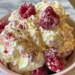 Close-up of a creamy frozen raspberry Greek yogurt in a bowl, with fresh raspberries on top.