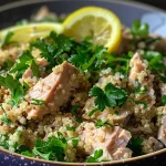 Um bowl de quinoa com atum, decorado com salsa fresca e fatias de limão.