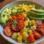 Salada de tomate e milho colorida com abacate em um prato.