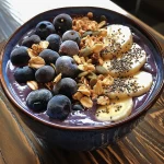 Tigela de smoothie de banana e mirtilo com granola e sementes de chia por cima.