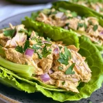 Close-up of vibrant chicken salad wrapped in large lettuce leaves.
