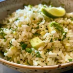 ['Close-up de uma porção de arroz com abacate em um prato.', 'Arroz branco com abacate e coentro, servido em uma tigela.', 'Imagem de arroz com abacate, limão e ervas frescas.', 'Detalhe de um prato de arroz com pedaços de abacate.']