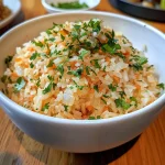 ['Prato de arroz com coco suculento e apetitoso.', 'Close de um prato de arroz com coco decorado.', 'Porção de arroz com coco apresentada de lado.', 'Arroz com coco servido em um prato branco.']