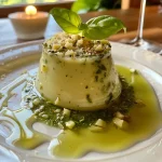 ['Close-up de Panna Cotta de Parmesão com Pesto de Manjericão e crocante.', 'Panna Cotta de Parmesão acompanhada de pesto verde e bolinhas crocantes.', 'Deliciosa Panna Cotta de Parmesão com pesto de manjericão e decoração crocante.', 'Vista lateral da Panna Cotta de Parmesão com pesto e pinhão tostado.']