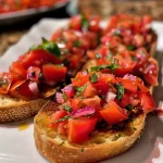 ['Close-up de bruschetta com tomates e manjericão.', 'Bruschetta colorida sobre fatias de baguete tostadas.', 'Porção de bruschetta com ingredientes frescos e vibrantes.', 'Bruschetta com mistura de tomates e ervas sobre pão.']