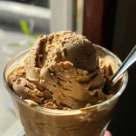 ['Café gelado cremoso em um copo com chantilly e brilho comestível.', 'Close-up de uma bebida gelada de café com leite condensado e chantilly.', 'Café gelado decorado com chantilly e glitter comestível em um fundo claro.', 'Copo de café gelado cremoso, coberto com creme e brilho, em vista lateral.']