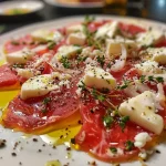 ['Carpaccio de beterraba com queijo de cabra e nozes em um prato.', 'Prato de carpaccio de beterraba decorado com queijo e nozes.', 'Close-up de carpaccio de beterraba com queijo de cabra fresco.', 'Carpaccio à base de beterraba, queijo de cabra e nozes em um fundo elegante.']