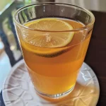 ['Chá de limão com mel e gengibre em um copo transparente, decorado com rodelas de limão.', 'Close de uma bebida quente de chá de limão, mel e gengibre, com fatias de gengibre ao lado.', 'Copo de chá de limão, mel e gengibre, com vapor subindo e rodelas de limão decorativas.', 'Imagem lateral de chá de limão com mel e gengibre, mostrando ingredientes frescos ao fundo.']