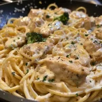 ['Prato de Frango Alfredo Cremoso com espaguete e ervas.', 'Close-up de uma porção de Frango Alfredo Cremoso, com queijo parmesão e brócolis.', 'Frango Alfredo Cremoso servido em um prato branco, com molho cremoso.', 'Espaguete com Frango Alfredo Cremoso, decorado com manjericão fresco.']