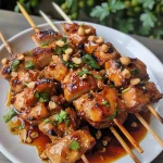 ['Cubos suculentos de frango grelhados com molho de amendoim ao lado.', 'Peitos de frango em espetos, servidos com molho de amendoim cremoso.', 'Satay de frango com molho de amendoim, decorado com cebolinhas.', 'Frango grelhado acompanhado de molho de amendoim e ervas frescas.']