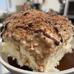 Bolo gelado de coco e chocolate em uma fatia, mostrando camadas cremosas.