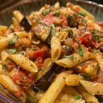 Prato de Penne Alla Norma com berinjela e molho de tomate.