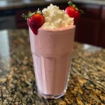 Shake de morango proteico em um copo transparente.